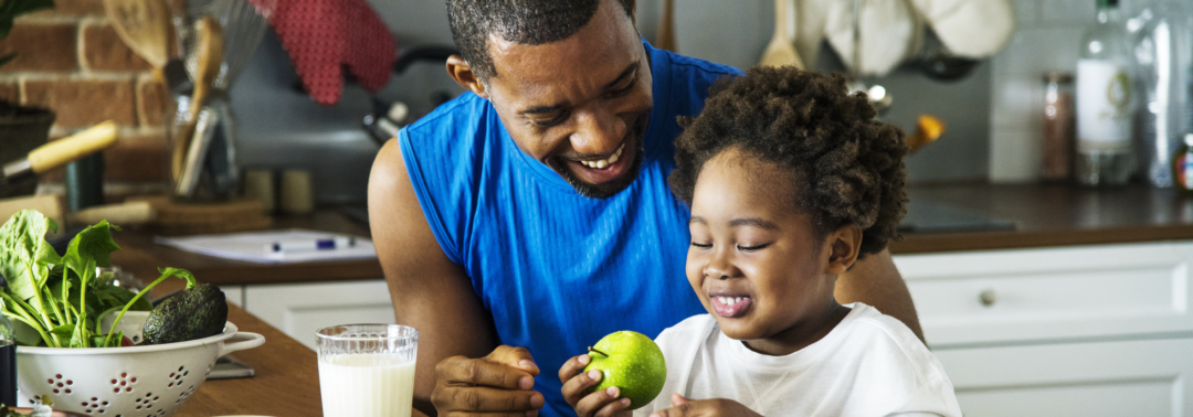 black man in the kitchen having fun cooking with his daughter.