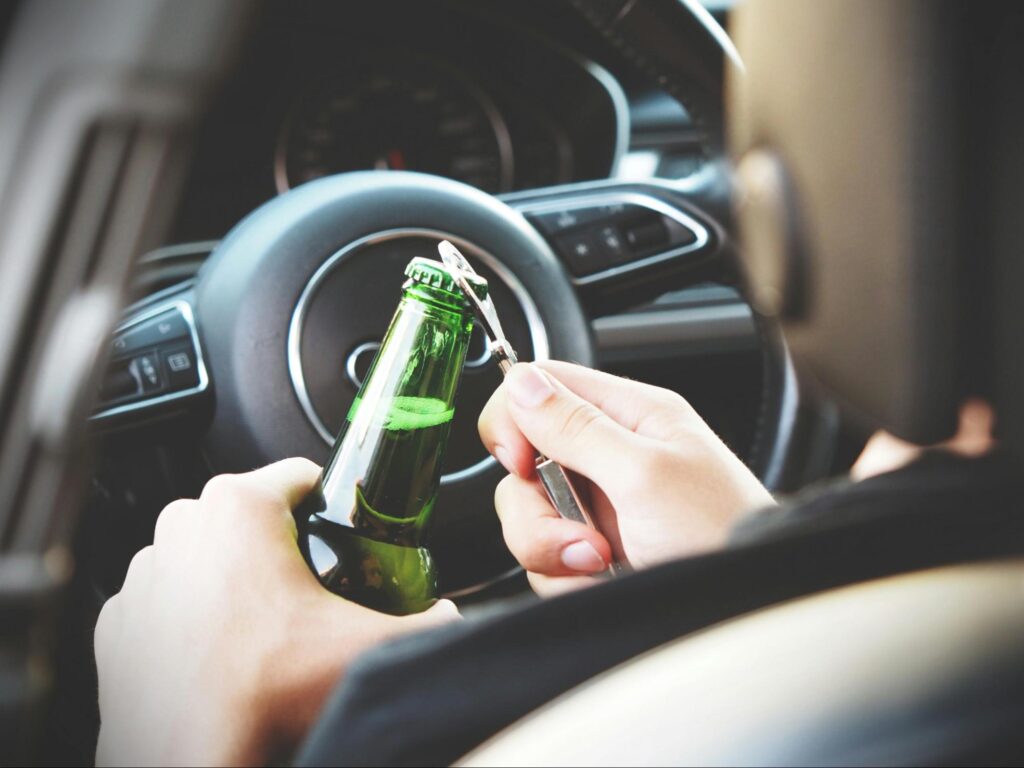 Addict opening a green bear bottle inside of a car