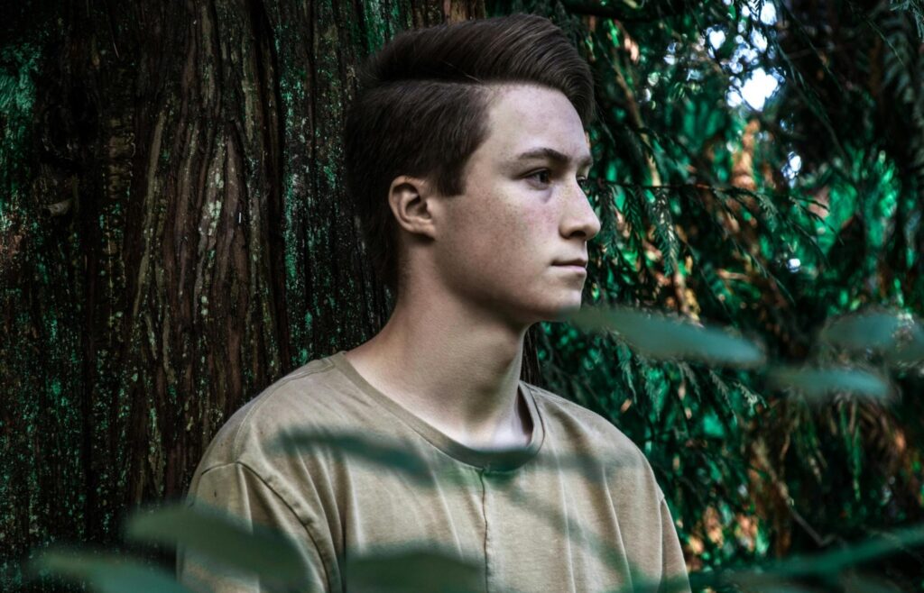 Sober man sitting in a Portland Oregon forest looking into the distance